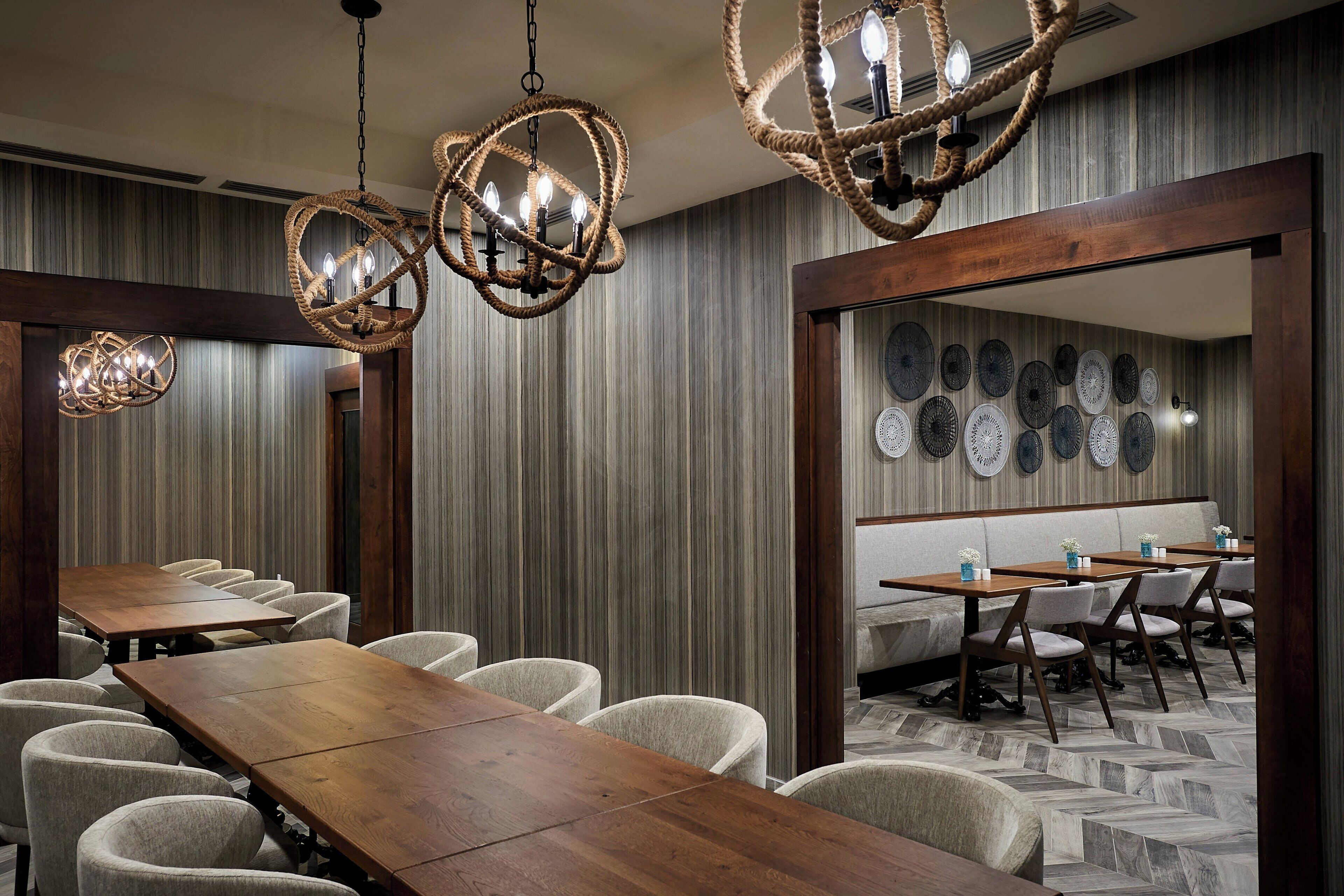 A conference room with a long wooden table, several upholstered chairs, and a wall decorated with circular plates.