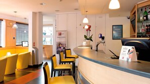 Un vestíbulo de hotel con mostrador de recepción, zona de estar y bar.