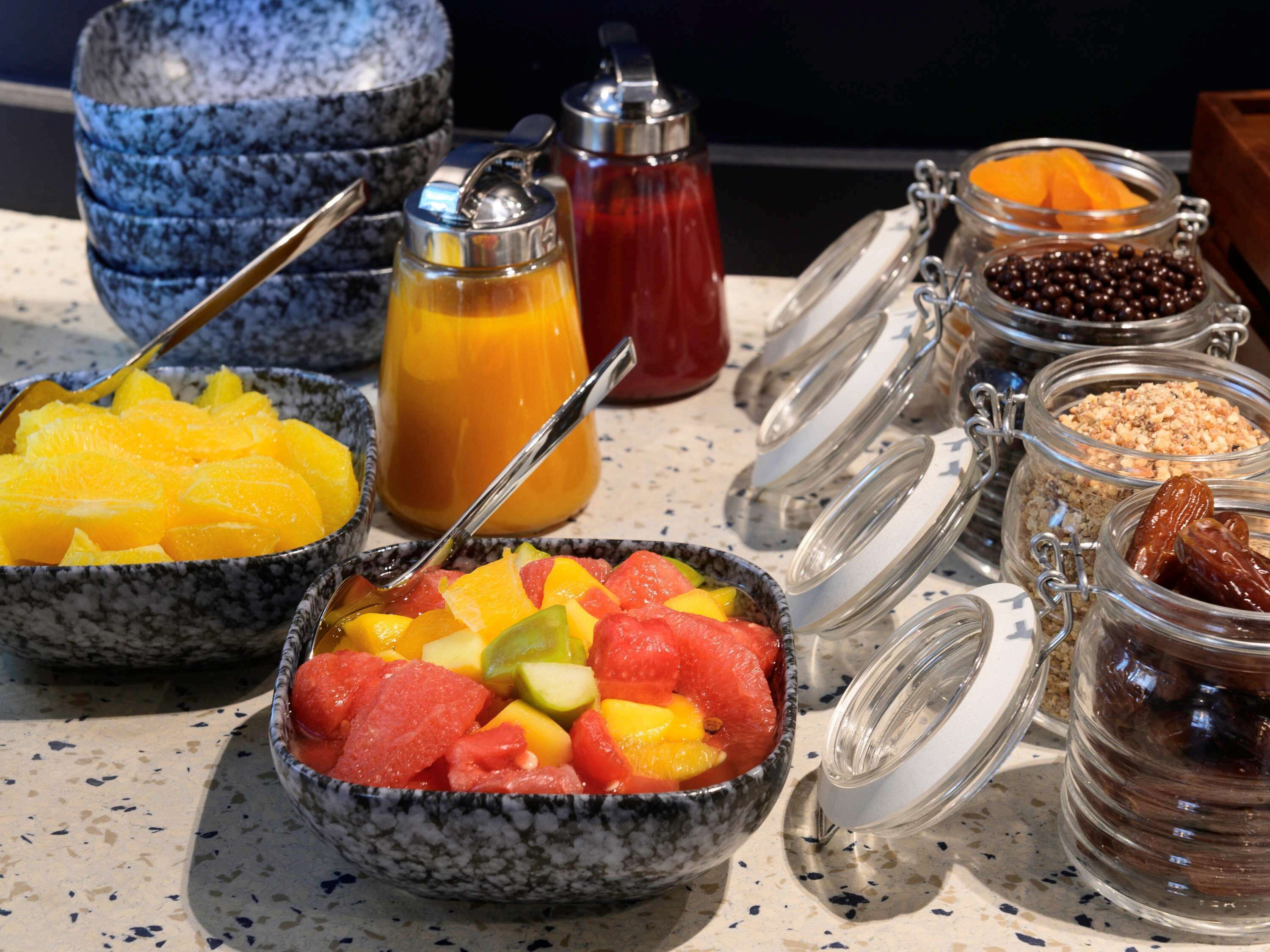 Un bufé de desayuno con diversas frutas, jugos y acompañamientos.