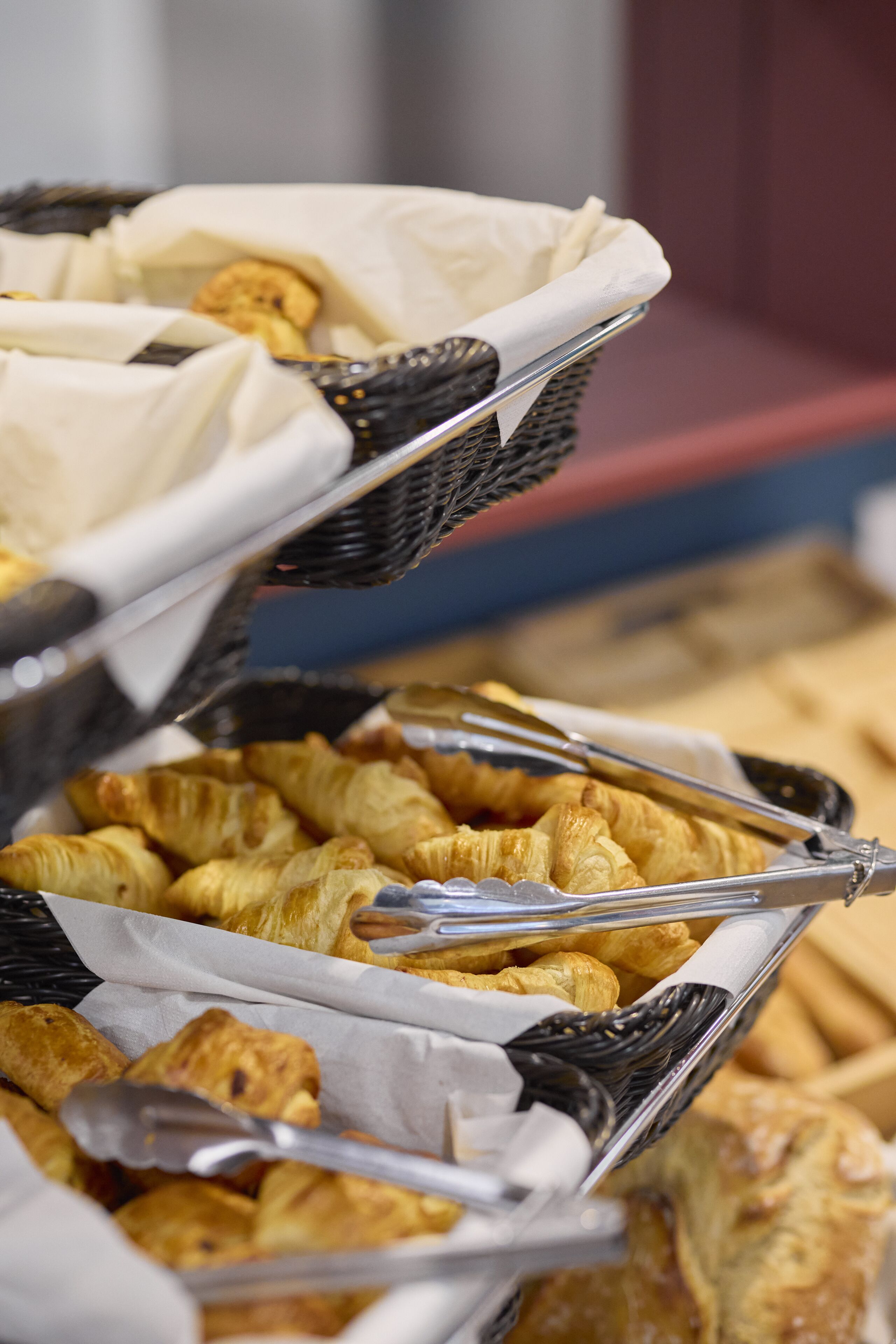 Un buffet avec des paniers de viennoiseries et des pinces.