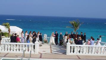 A wedding ceremony on a poolside deck with a view of the ocean.