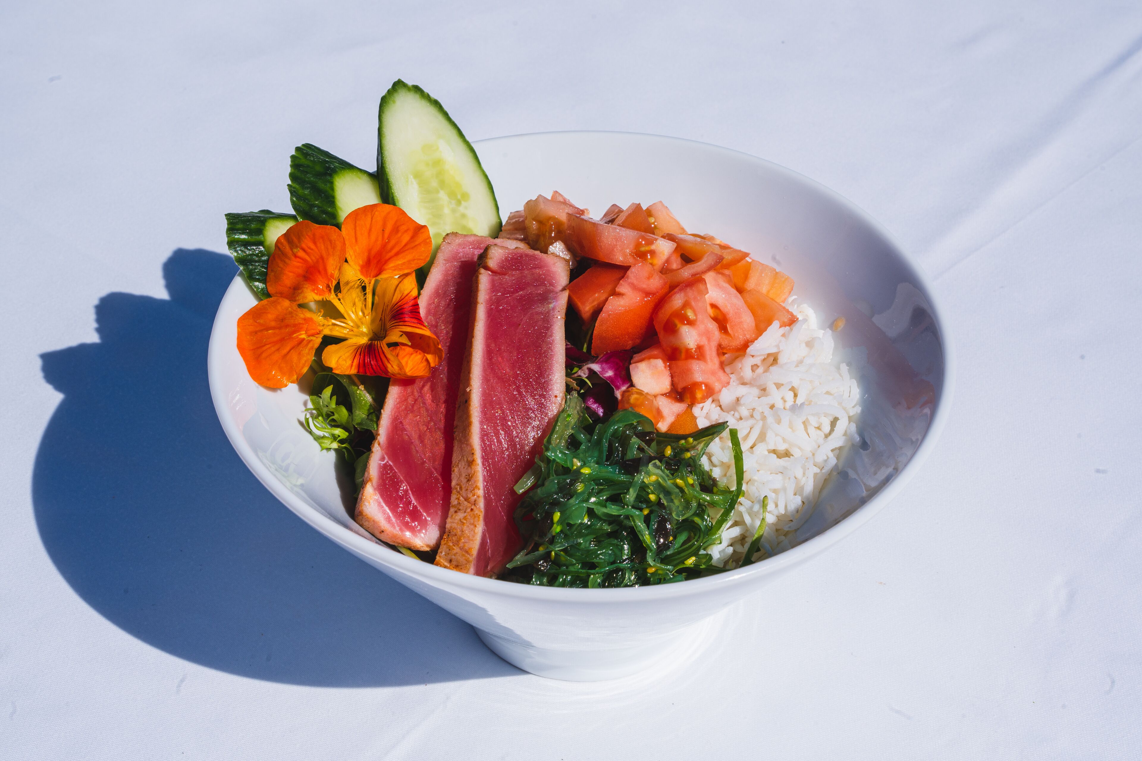 A bowl of food with various ingredients including vegetables, rice, and meat.