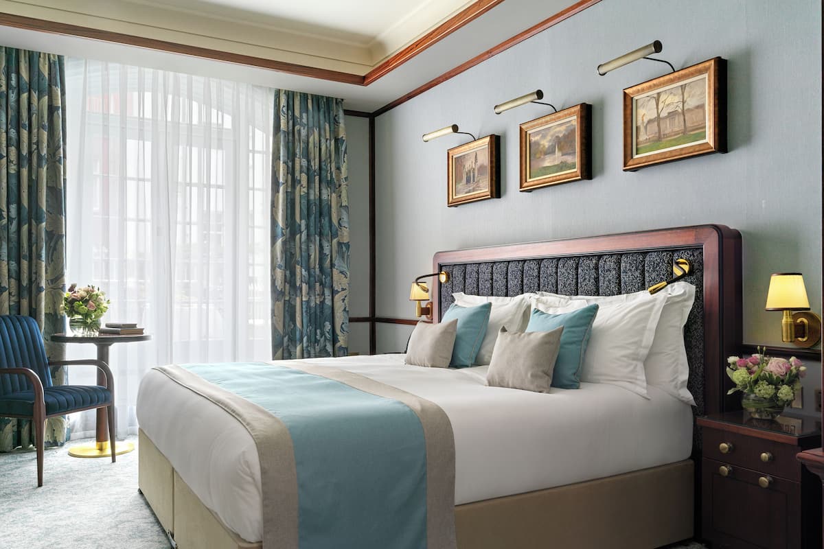 A neatly made bed with a blue and beige bedspread, a wooden headboard, and a nightstand with a lamp.