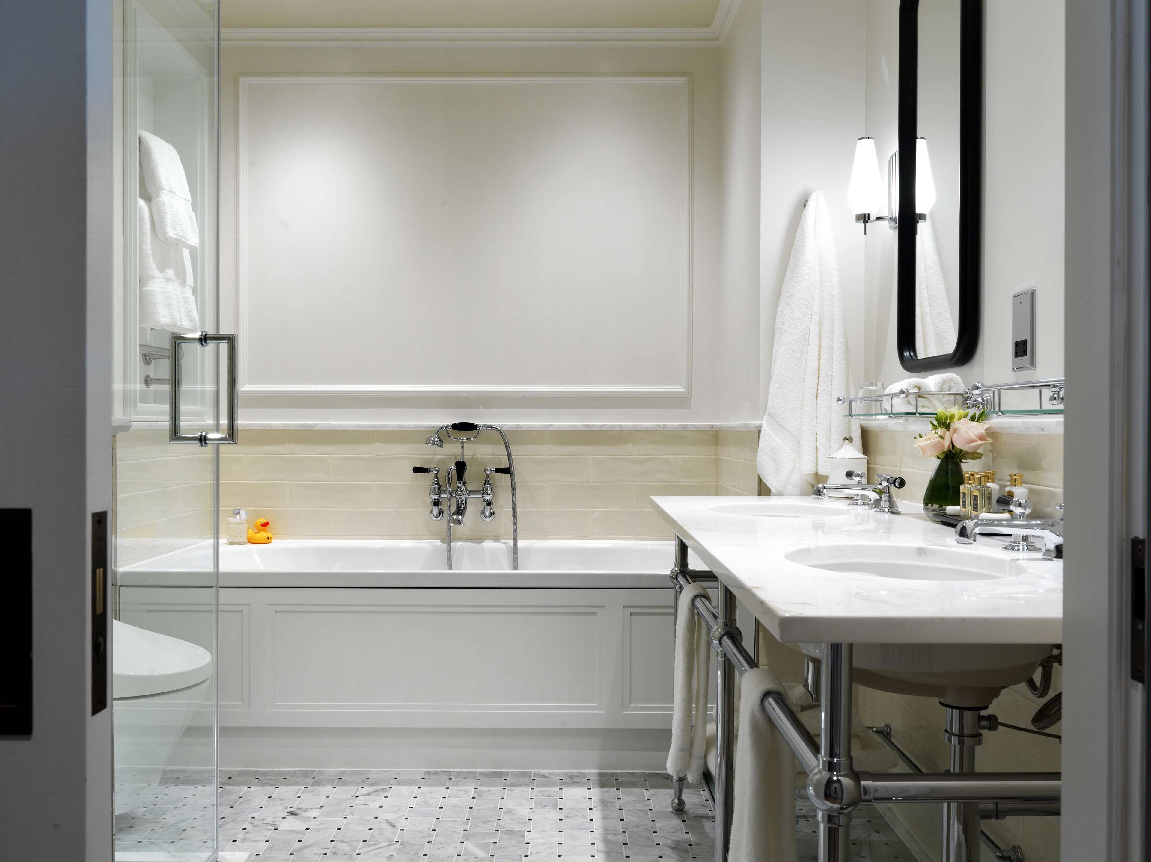 A modern bathroom with a bathtub, two sinks, and a large mirror.
