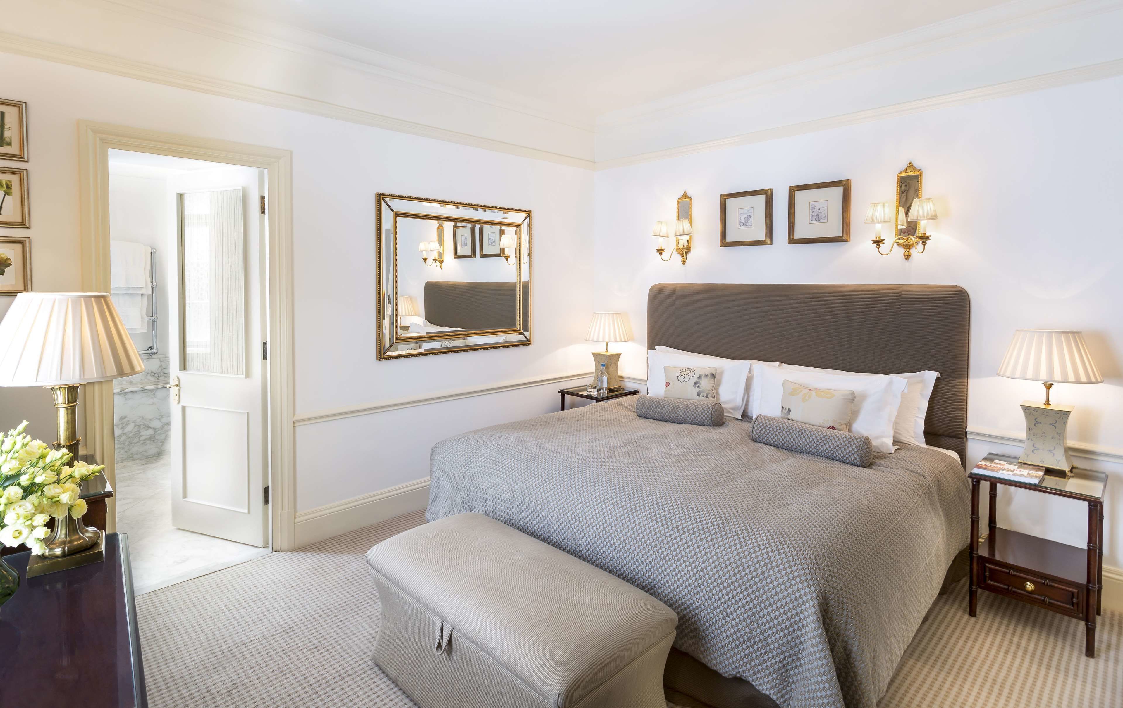 Ein Hotelzimmer mit einem großen Bett, einem Nachttisch, einem Spiegel und einer Tür zu einem Badezimmer.