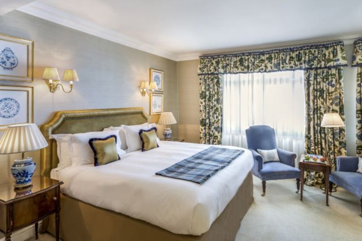 A hotel room with a large bed, two bedside tables, a chair, and a small table.