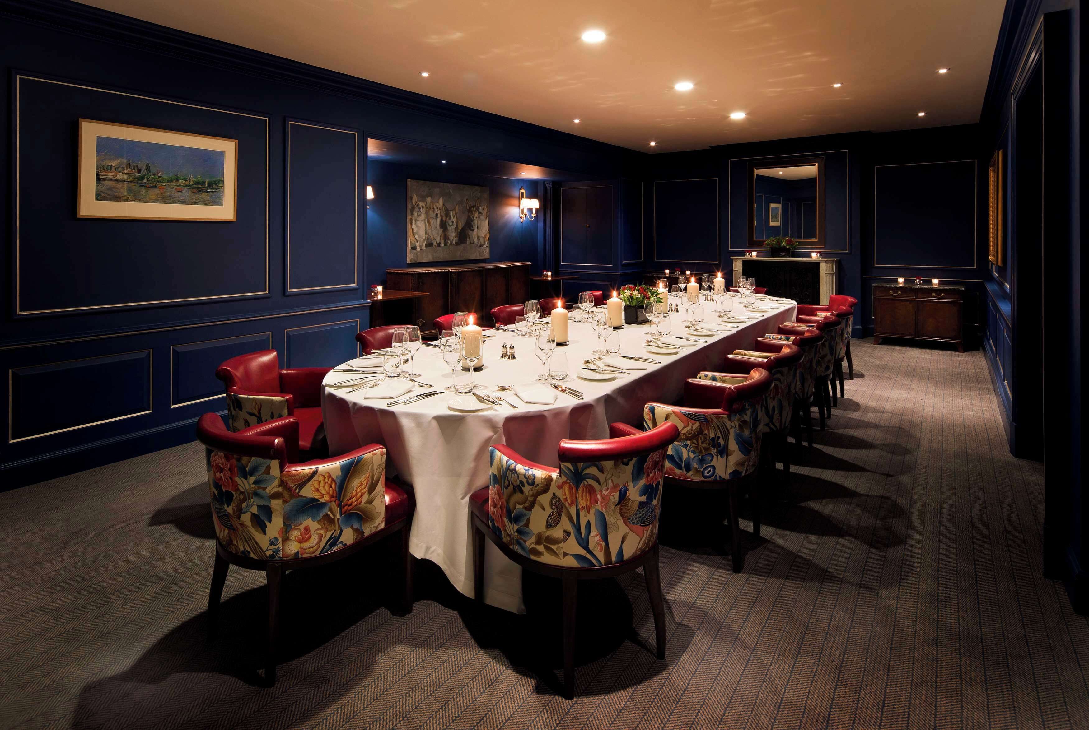 A long dining table set with candles, surrounded by red upholstered chairs with floral patterns.