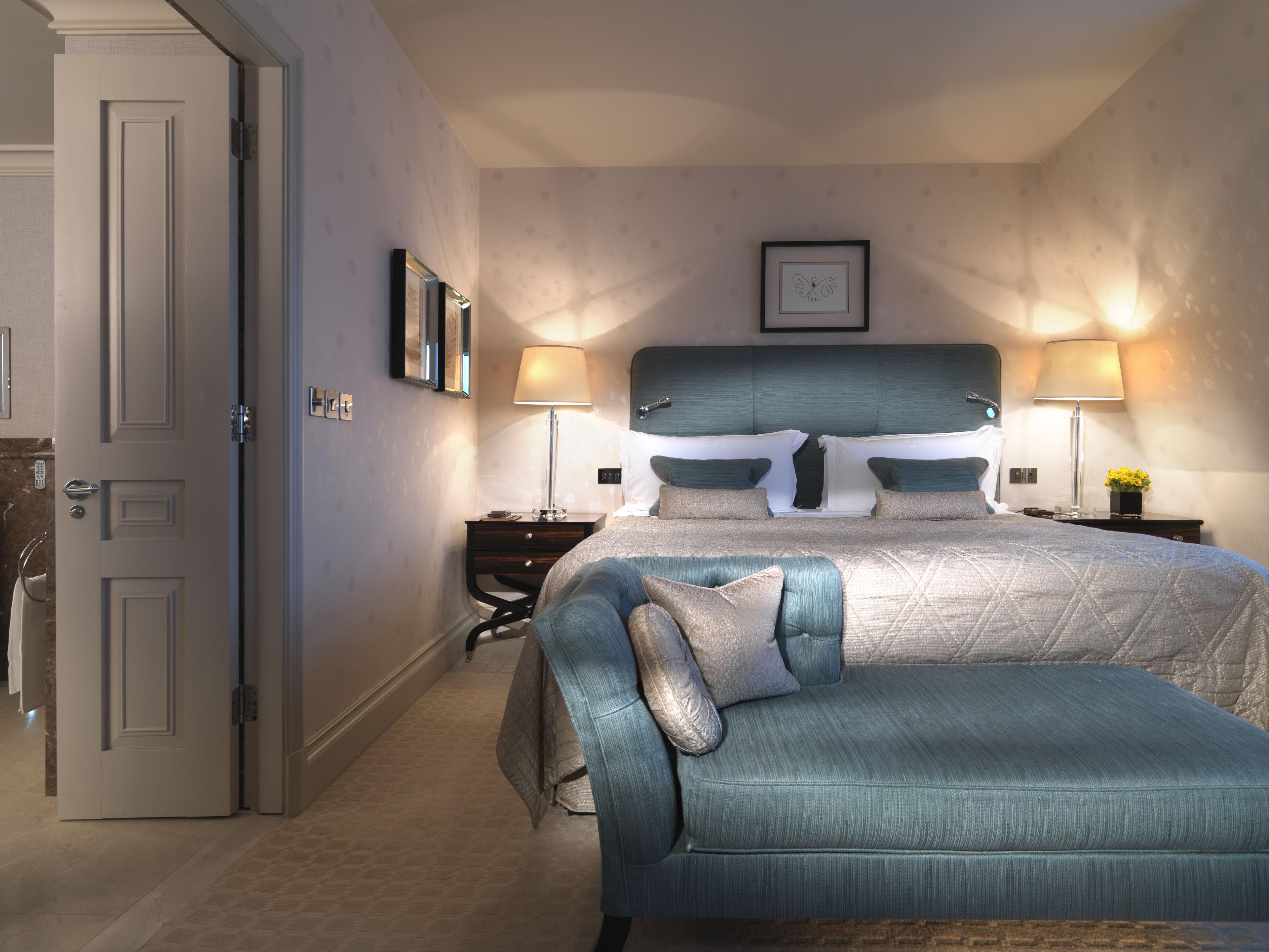 Ein Schlafzimmer mit einem großen Bett, zwei Nachttischen, einer Kommode und einem an der Wand hängenden Bild.