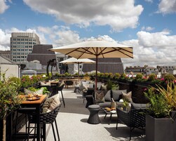 Eine Außenpatio-Terrasse mit Sitzgelegenheiten, Sonnenschirmen und Blumentöpfen.