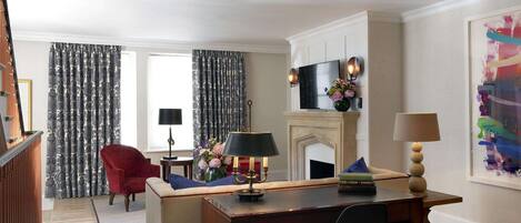 A living room with a fireplace, a red armchair, a wooden coffee table, and a black chair.
