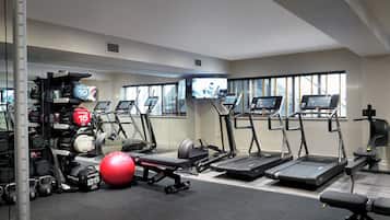 Ein Fitnessraum mit Laufbändern, Kraftgeräten und einem roten Trainingsball.