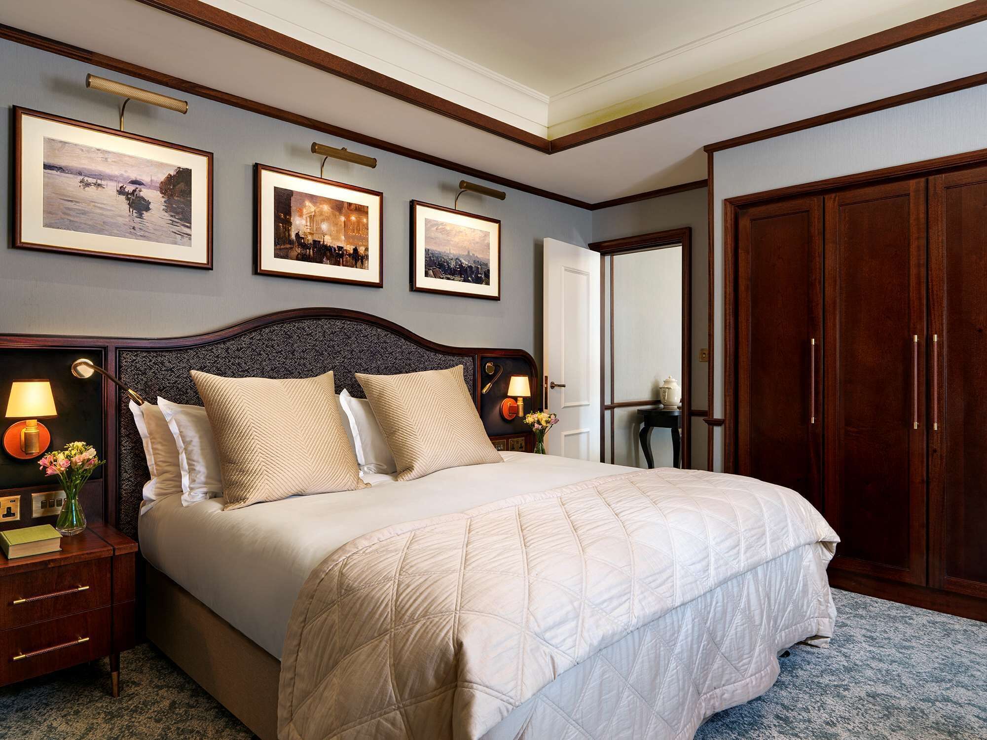 Ein ordentlich eingerichtetes Hotelzimmer mit einem großen Bett, einem Holz-Kopfteil und gerahmten Bildern an der Wand.