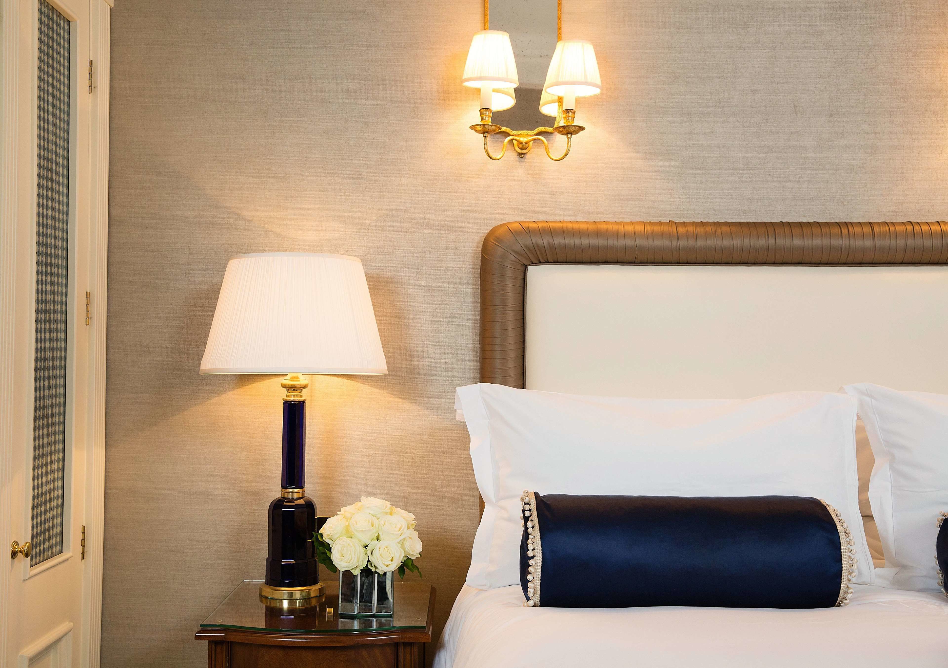 Ein Hotelzimmer mit Bett, Nachttisch mit Lampe und Wandleuchte.