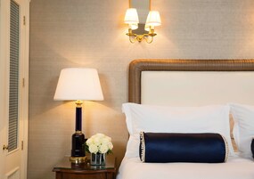 Ein Hotelzimmer mit Bett, Nachttisch mit Lampe und Wandleuchte.