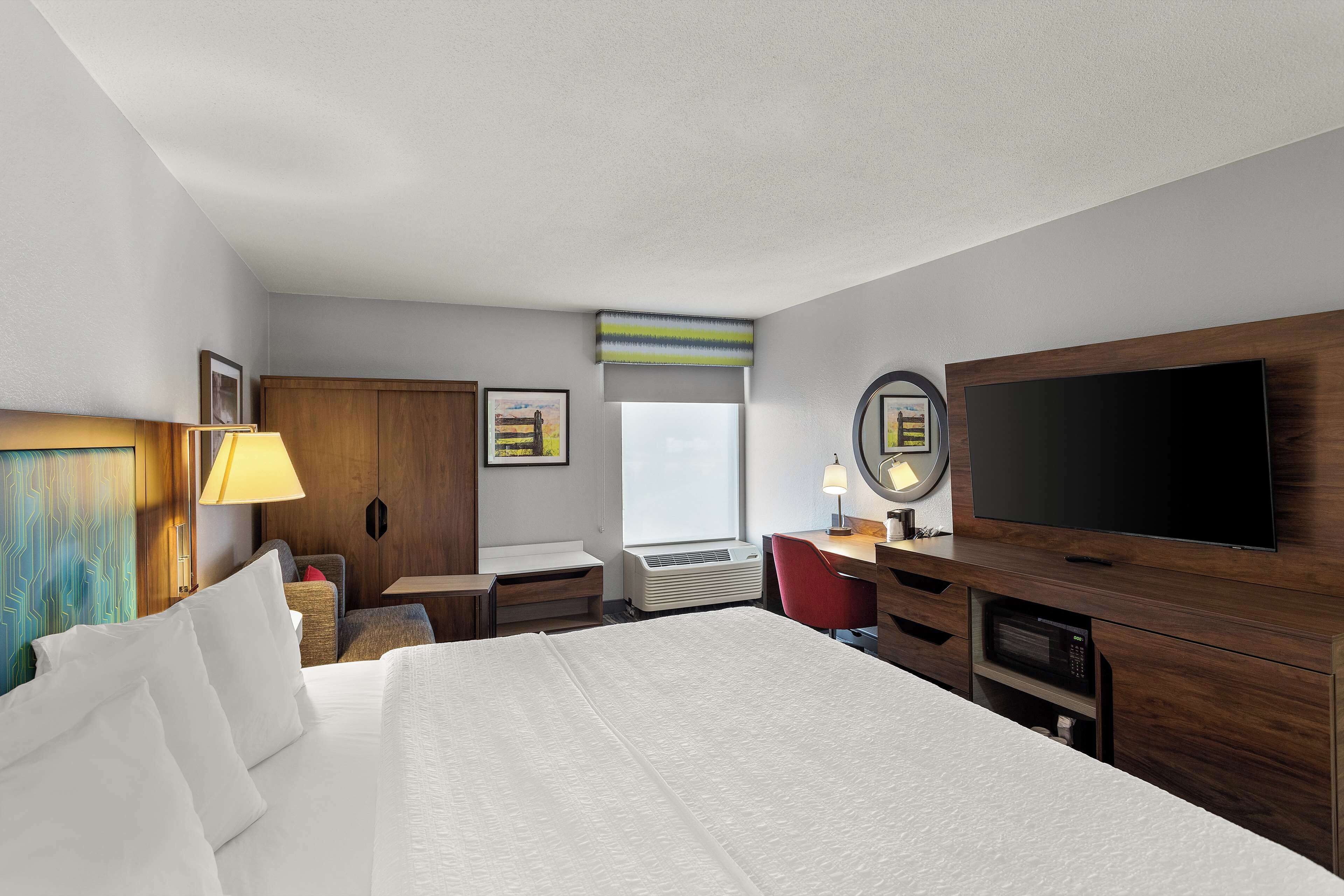 Une chambre d’hôtel avec un grand lit, un bureau, une télévision et une fenêtre.