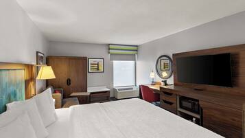 Une chambre d’hôtel avec un grand lit, un bureau, une télévision et une fenêtre.