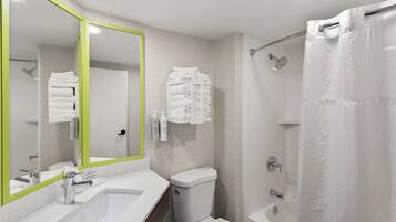A modern bathroom with a white sink, mirror, toilet, and shower area.