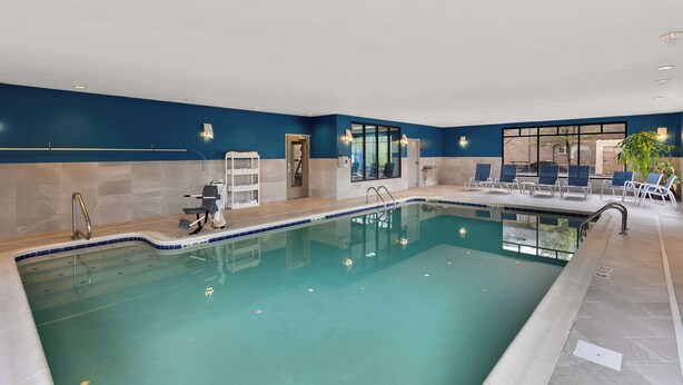 An indoor swimming pool with clear water, a tiled deck, and lounge chairs. - Hampton Inn Bridgeport/Clarksburg (Bridgeport)