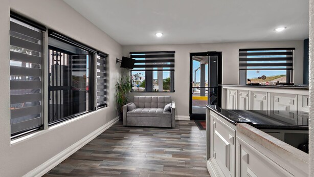 A modern kitchen with white cabinetry, a grey sofa, and large windows with blinds. - Econo Lodge Inn & Suites Laredo - Nuevo Laredo (Laredo)