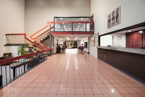 A spacious lobby with a red staircase, a reception desk, and a view into the dining area. - Red Roof Inn & Suites Lexington - Hamburg (Lexington)