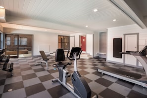 Une salle de sport équipée de matériel d’exercice, d’un tapis de course et dotée d’un sol à carreaux.