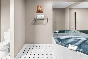 A bathroom with a toilet, a shower, and a bathtub. There is a towel rack on the wall and a painting above the shower.
