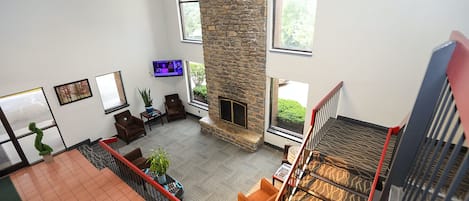 A spacious living area with a stone fireplace, large windows, and a view of the outdoors.