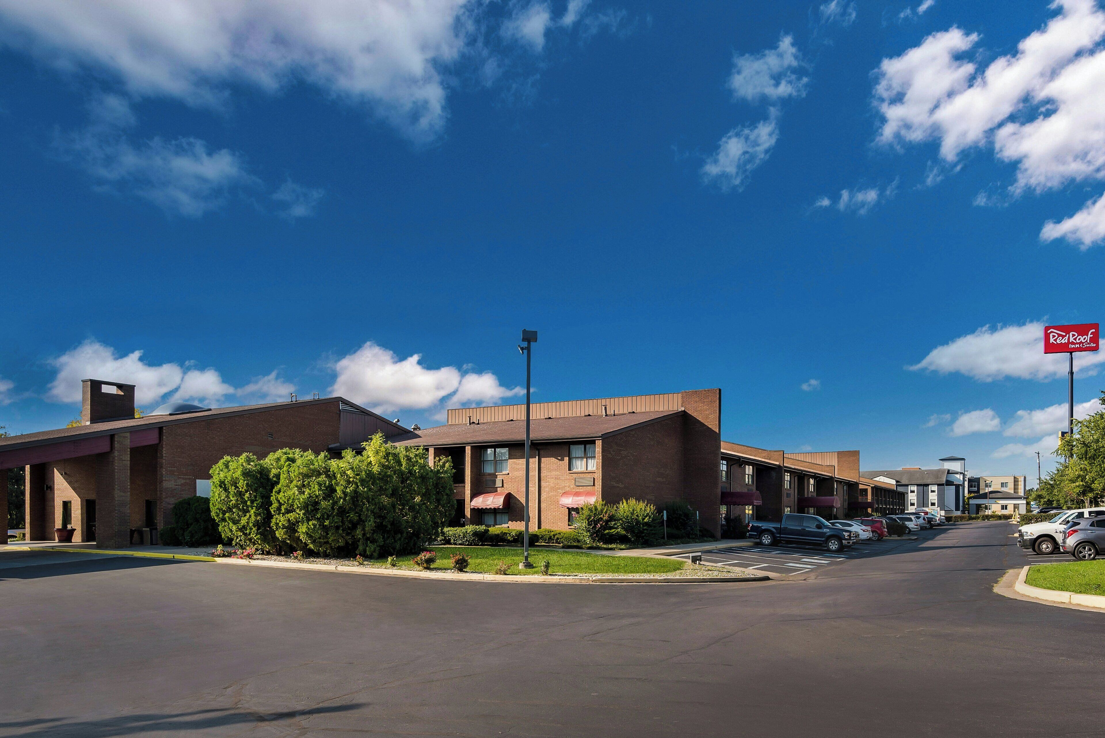 A hotel with a brick facade, a parking lot, and a clear blue sky.
