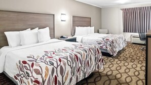 A hotel room with two beds, a desk, a chair, and a large window with curtains. - Red Roof Inn & Suites Lexington - Hamburg (Lexington)