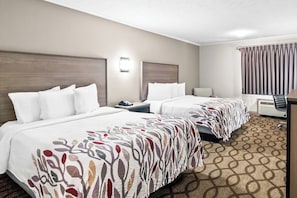 A hotel room with two beds, a desk, a chair, and a large window with curtains.