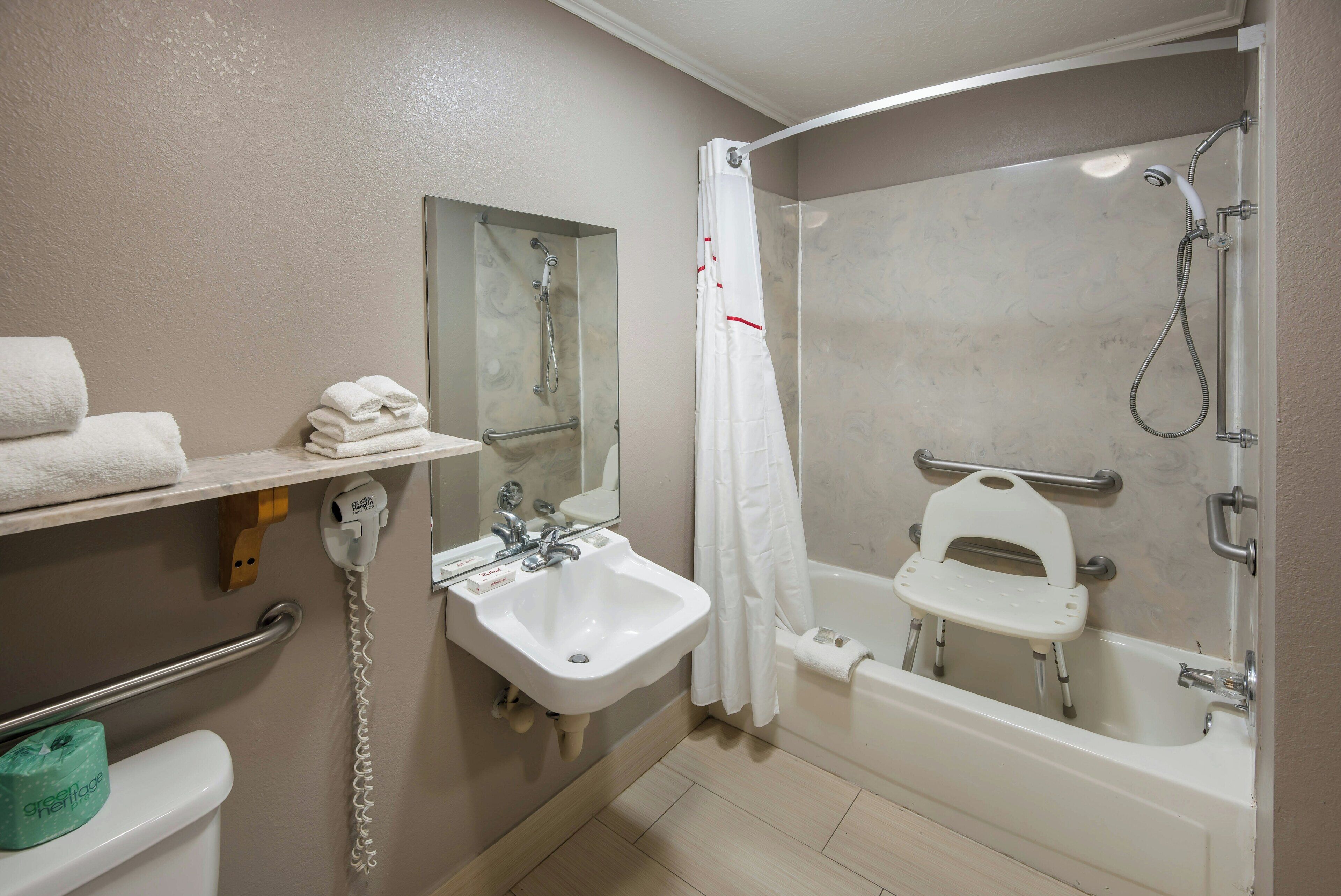 A bathroom with a sink, mirror, shower, and a toilet.
