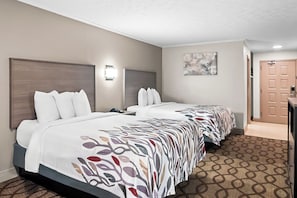 A hotel room with two beds, a desk, and a door.
