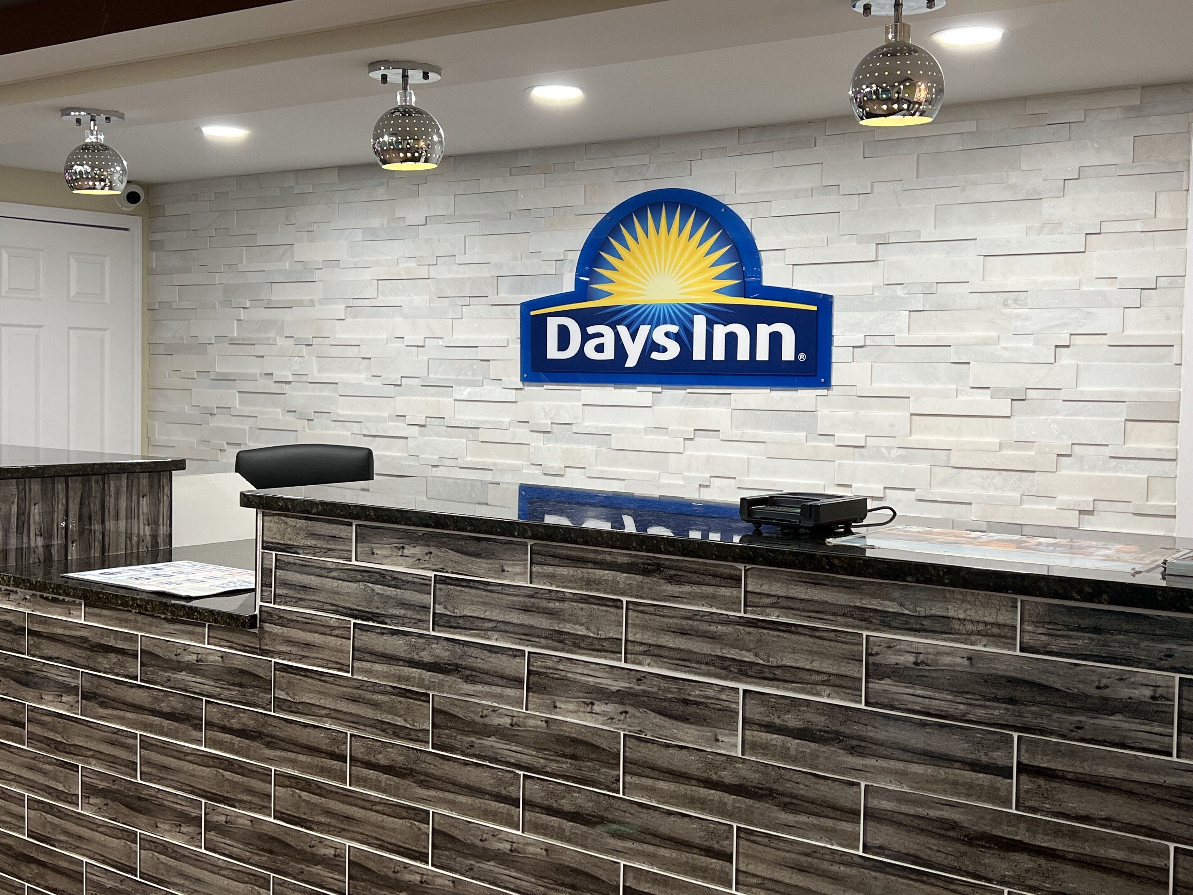 Un mostrador de recepción con el logotipo de Days Inn, una silla negra y una pantalla digital.
