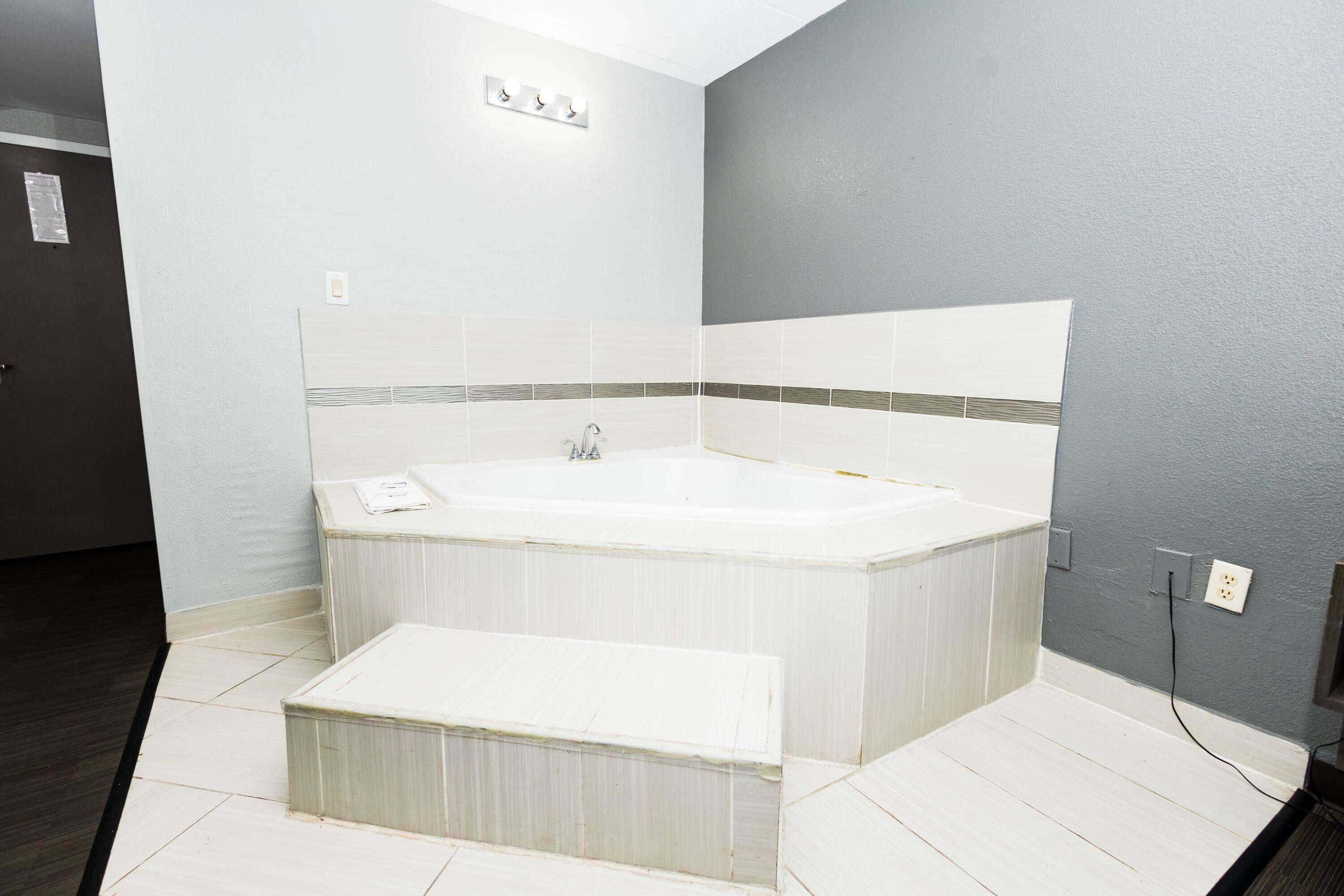 Ein modernes Badezimmer mit einer freistehenden Badewanne, einer kleinen Sitzbank und einer hellgrauen Wand.