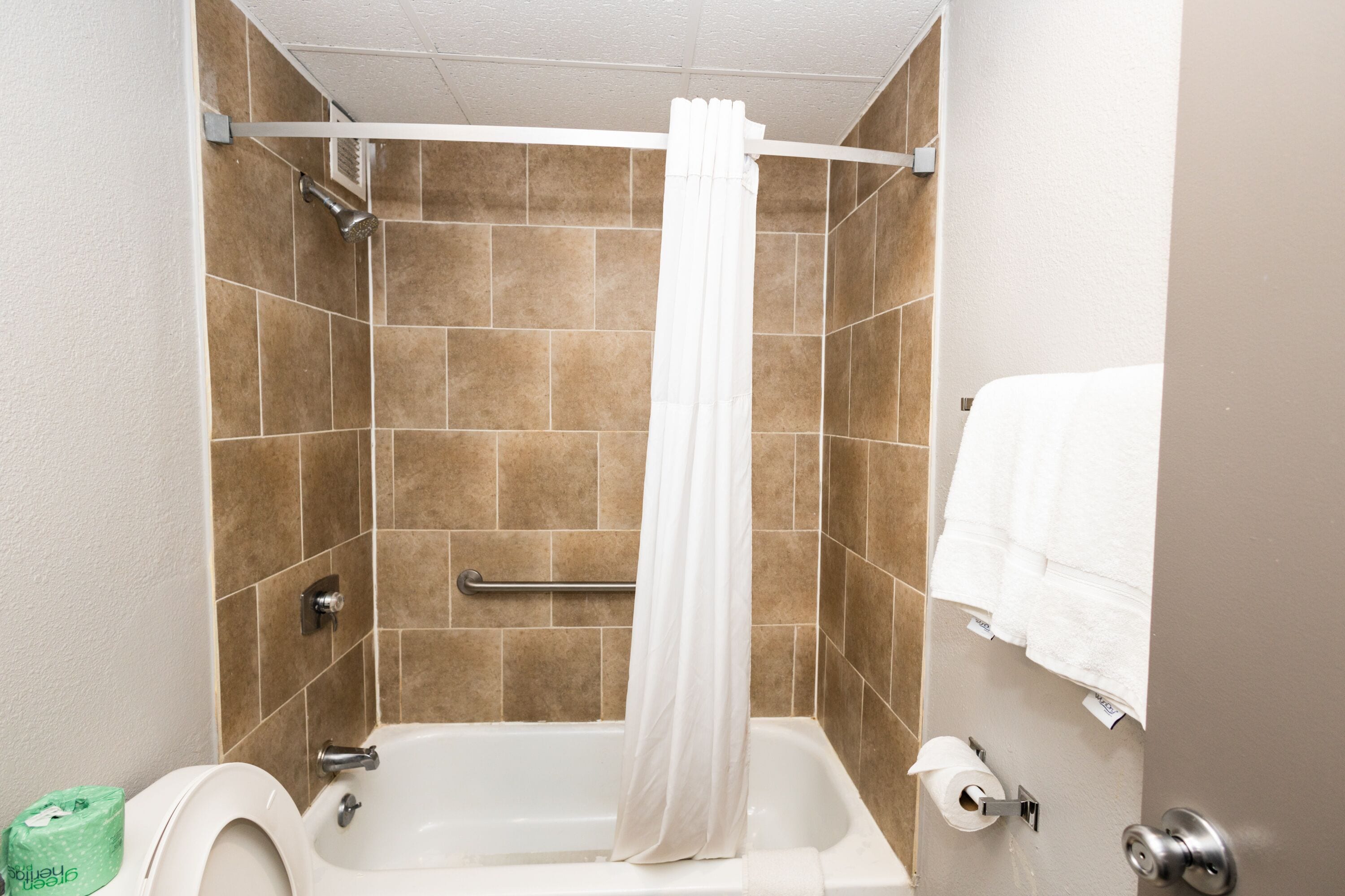 A bathroom with a bathtub, a shower curtain, a towel rack, and a toilet.