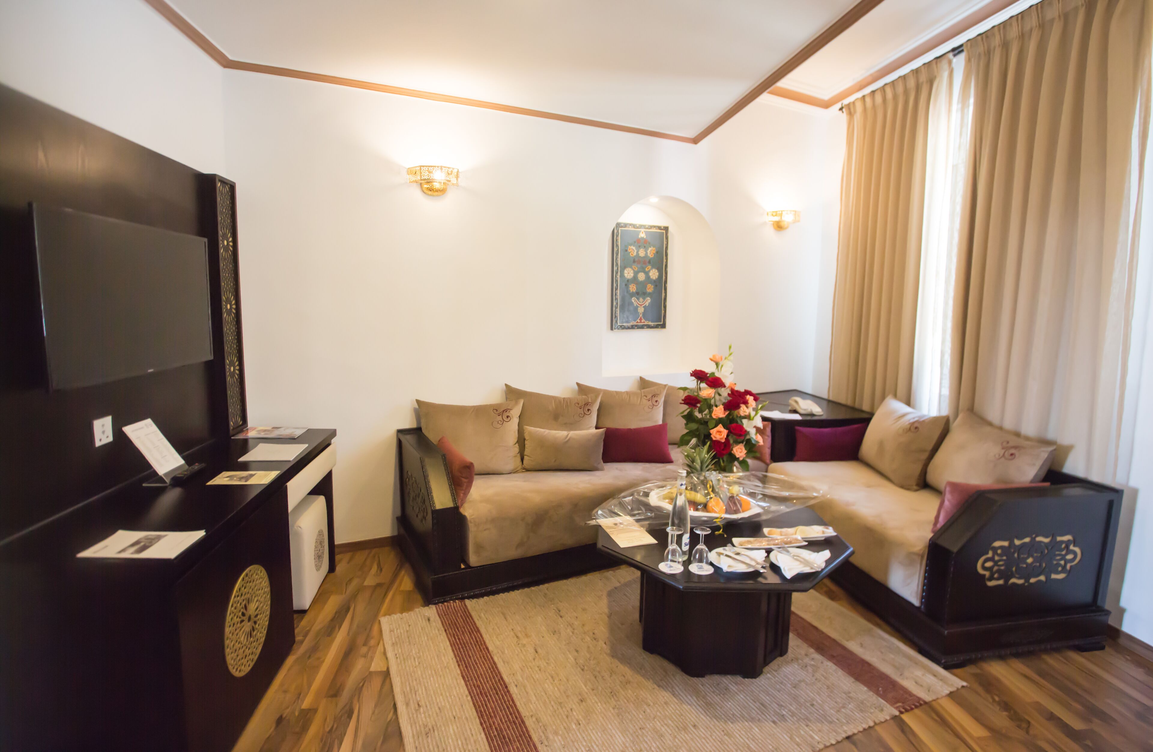 Una sala de estar con sofá, mesa de centro, televisor y un adorno en la pared.
