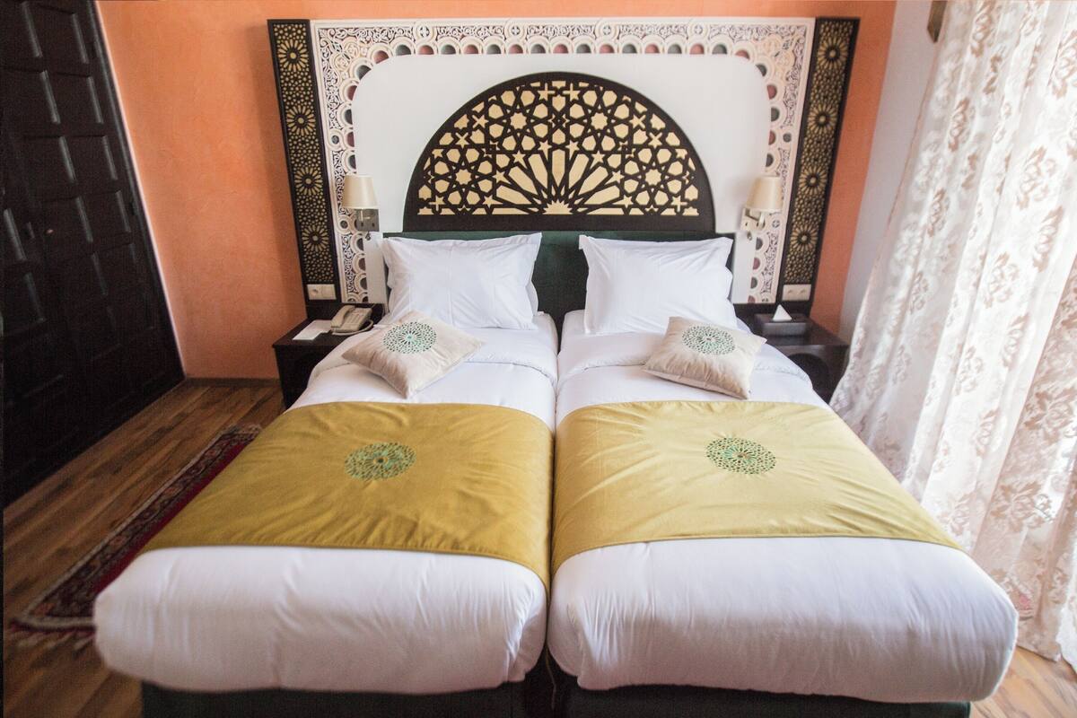 A double bed with a decorative headboard, two bedside tables, and a patterned rug on the floor.