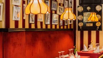 A dining area with tables set for service, framed pictures on the wall, and a vintage wall clock.