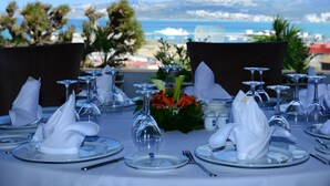 Una mesa preparada para comer, con vista al mar y montañas al fondo.