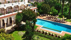 Un hotel con piscina, mobiliario exterior y vistas al mar.