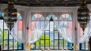 Una habitación lujosa con un ventanal grande, cortinas elegantes y faroles ornamentales.