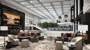A spacious lobby with a high ceiling, modern furniture, and a large digital display.