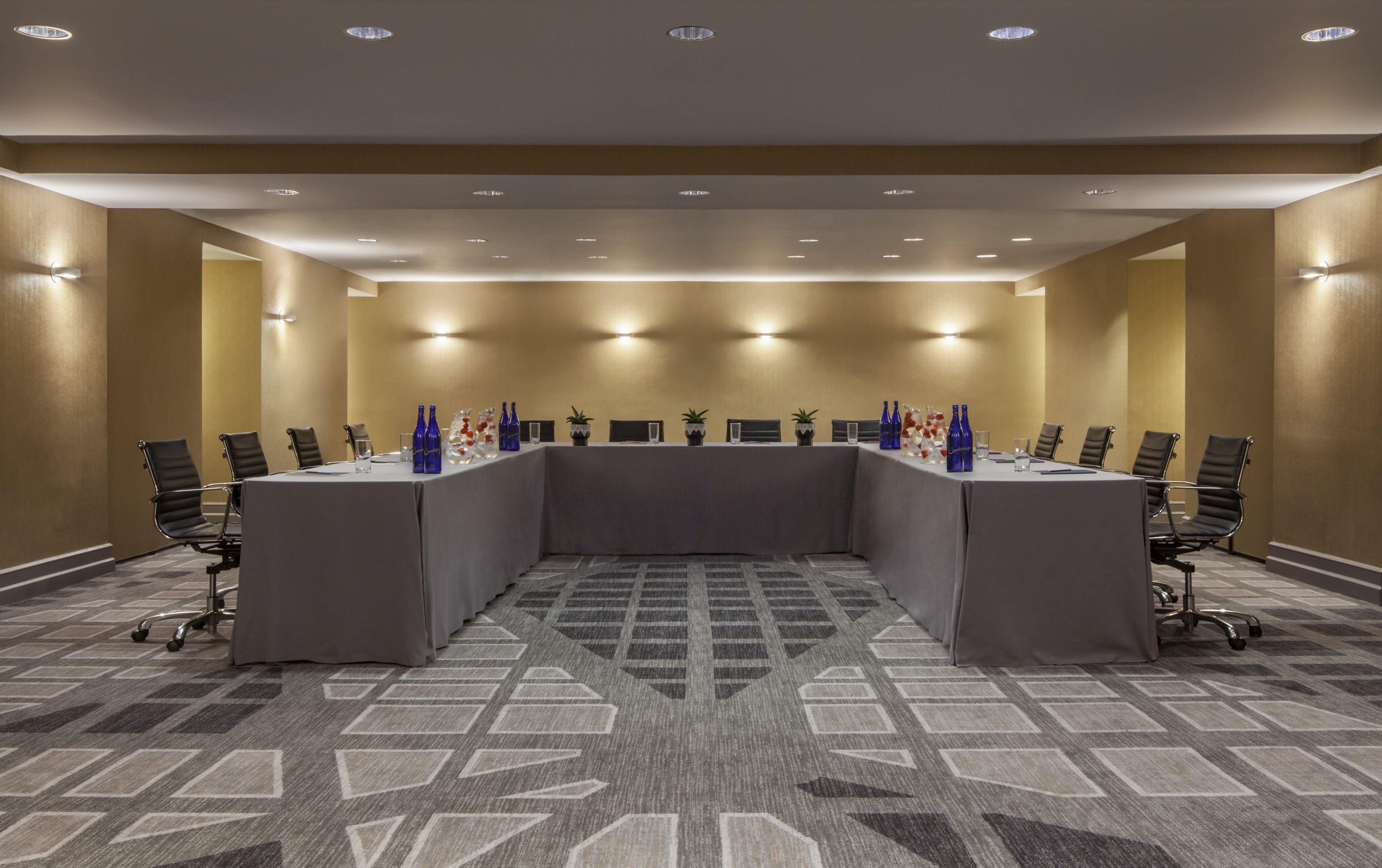 A conference room with a long table, chairs, and a carpeted floor.