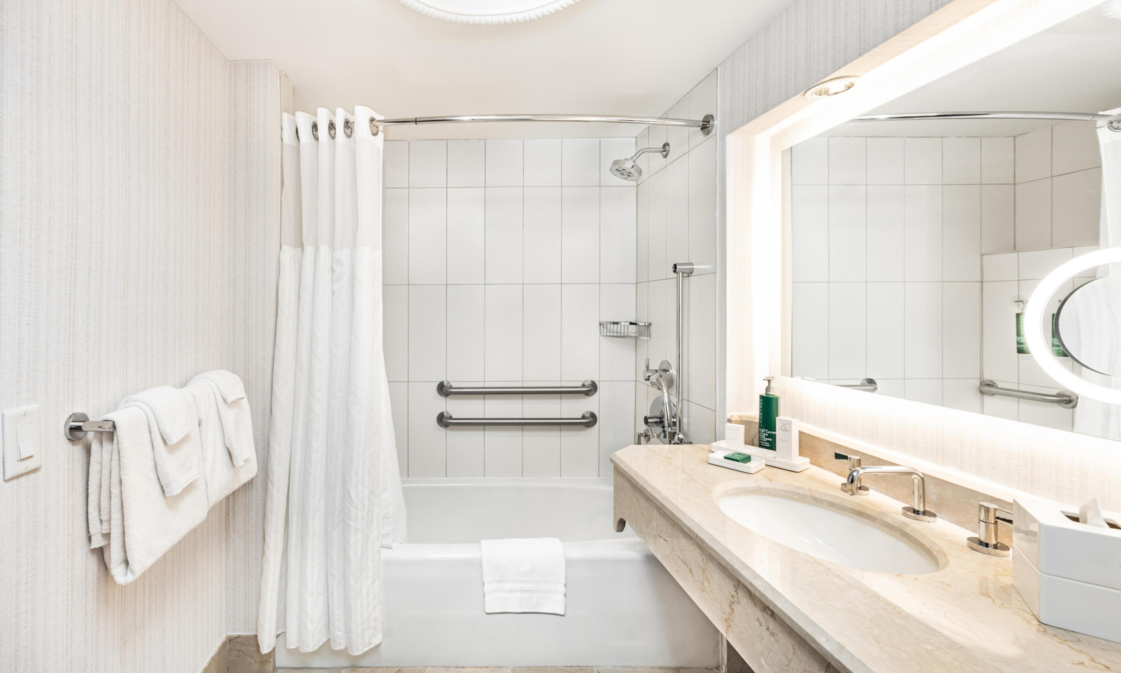 Un bagno moderno con doccia, vasca, mobile lavabo e uno specchio grande.