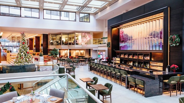 A spacious indoor area with a bar and seating areas, featuring a glass ceiling and multiple levels.
