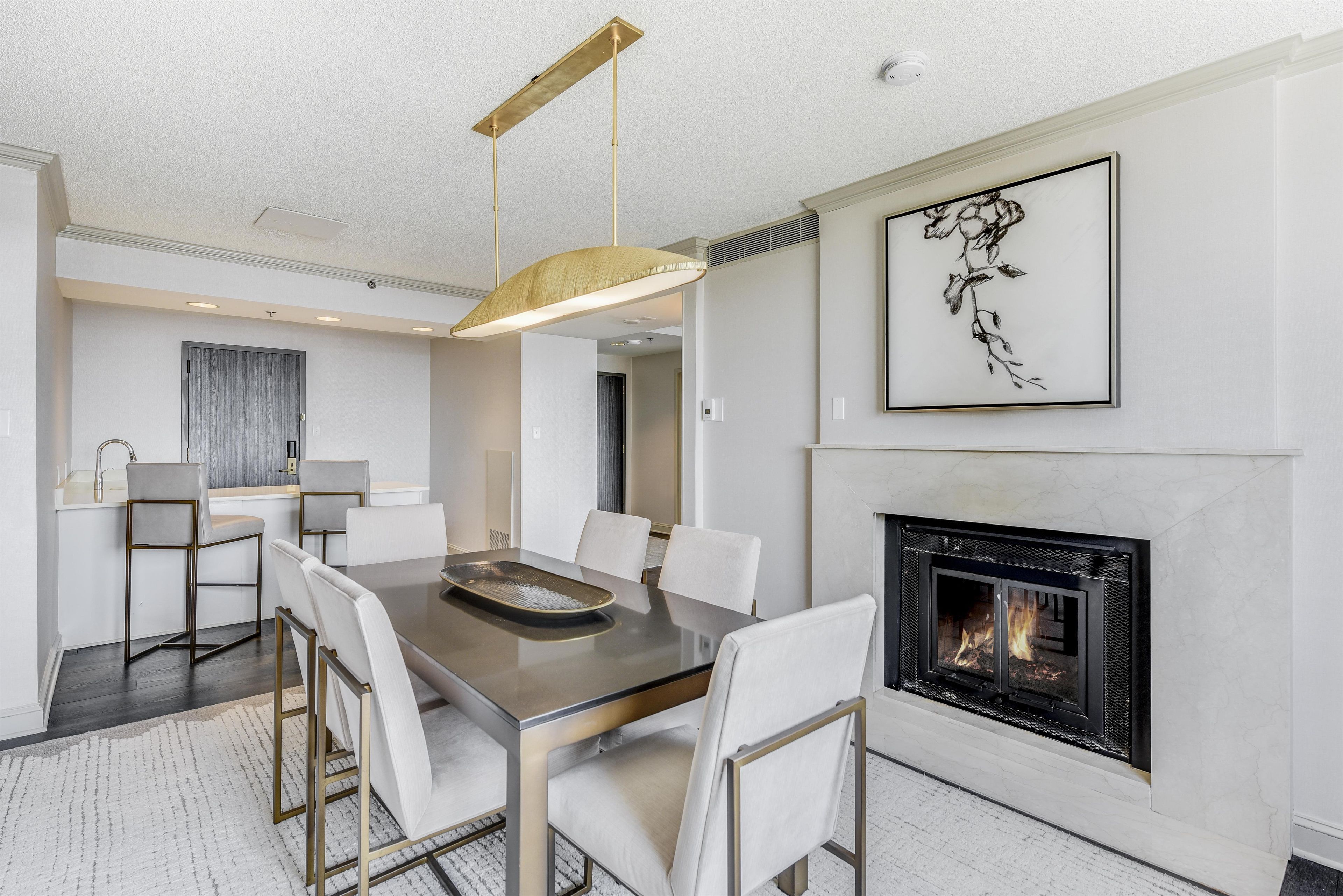 A modern dining area with a fireplace, a chandelier, and a framed artwork on the wall.