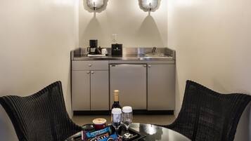 A compact kitchen with a sink, a coffee maker, and a wine bottle on a tray.