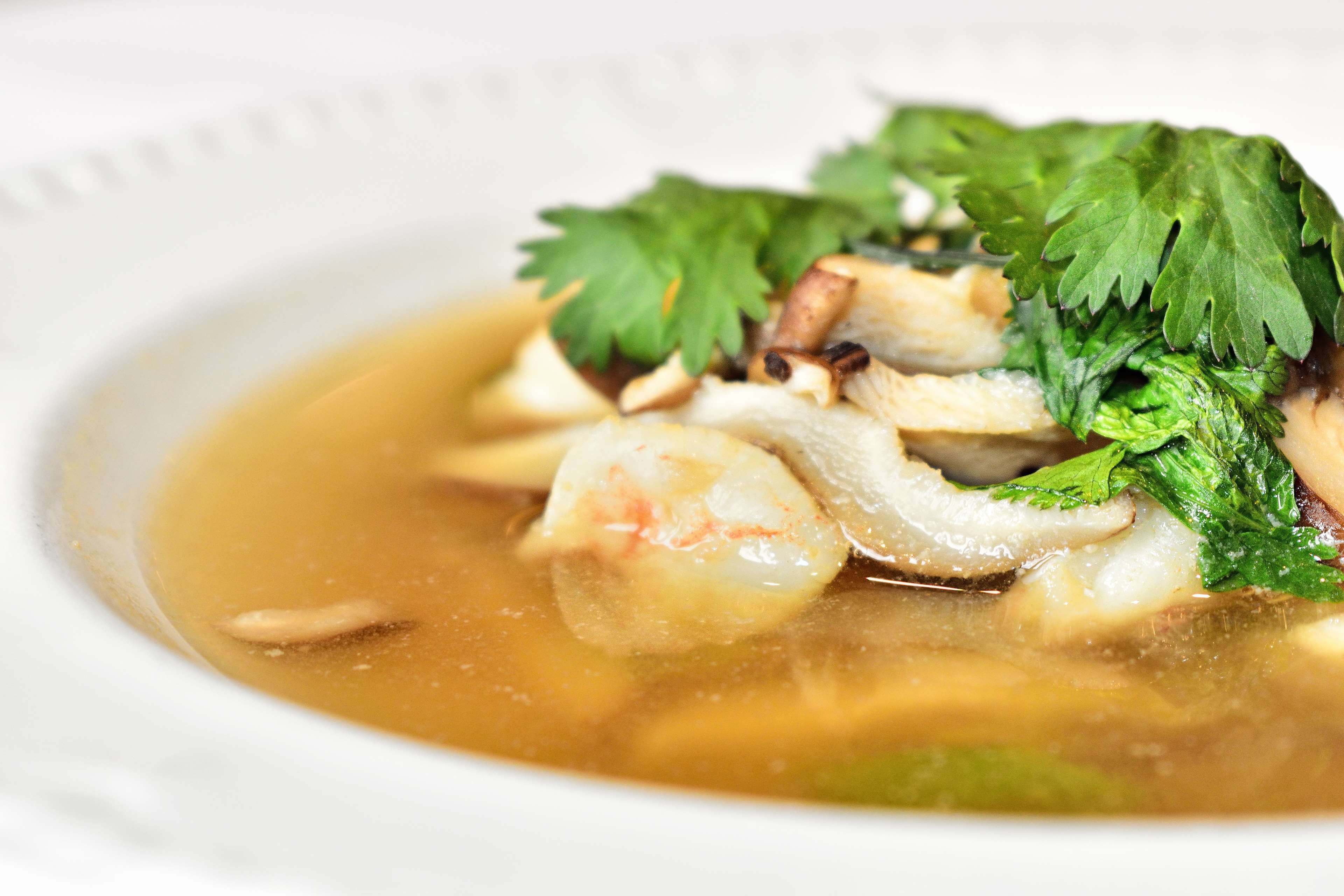 Eine Schale Suppe mit Meeresfrüchten und Kräutern.