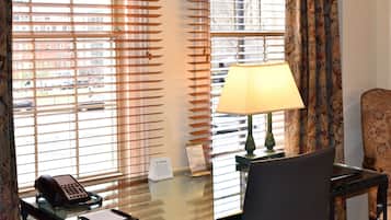 A hotel room with a desk, a telephone, a lamp, and a chair.