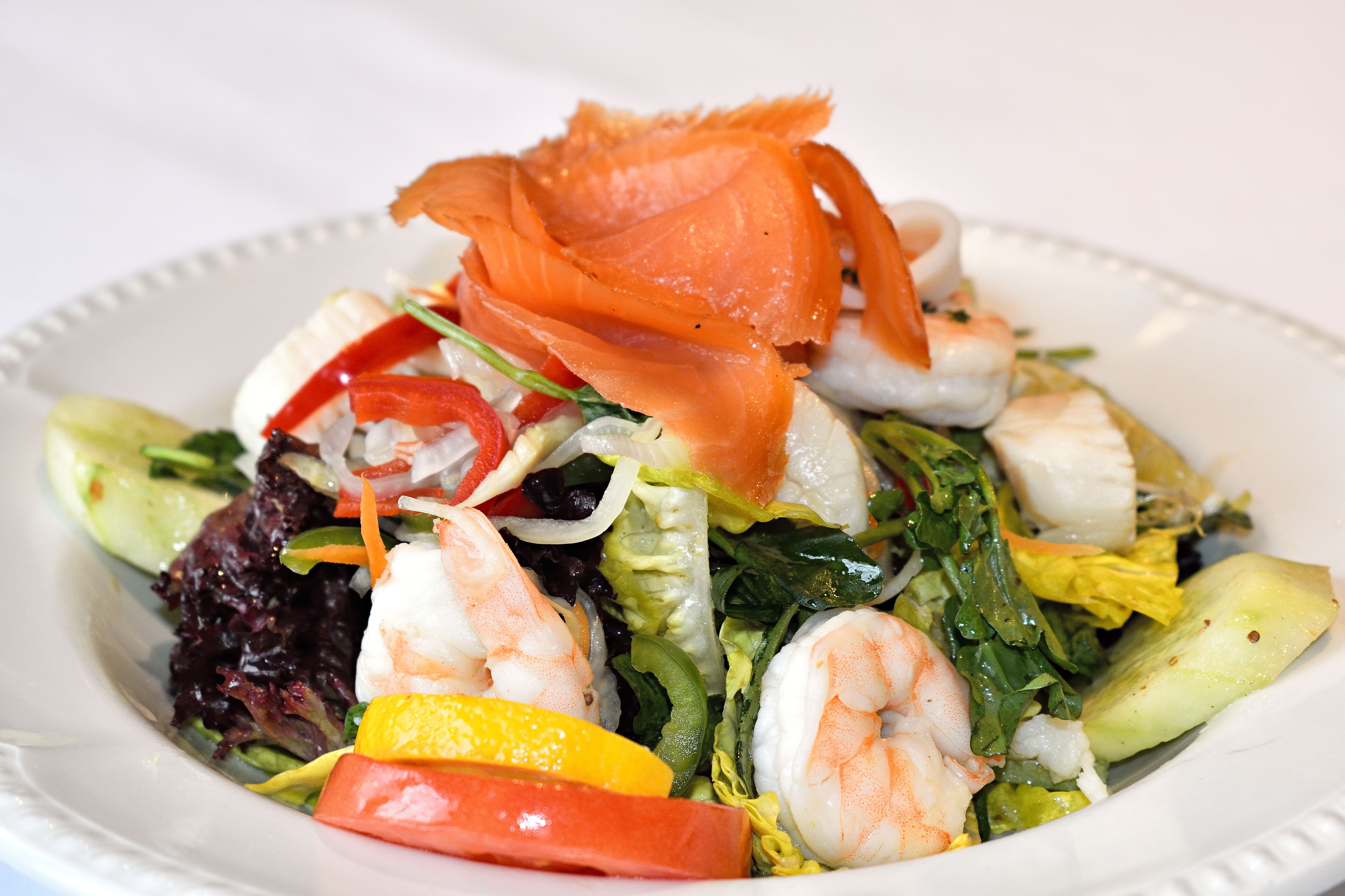 Ein Teller mit Garnelen, Gemüse und geräuchertem Lachs.